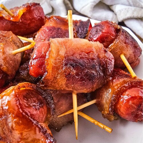 Bacon wrapped smokies in a pile on a plate.