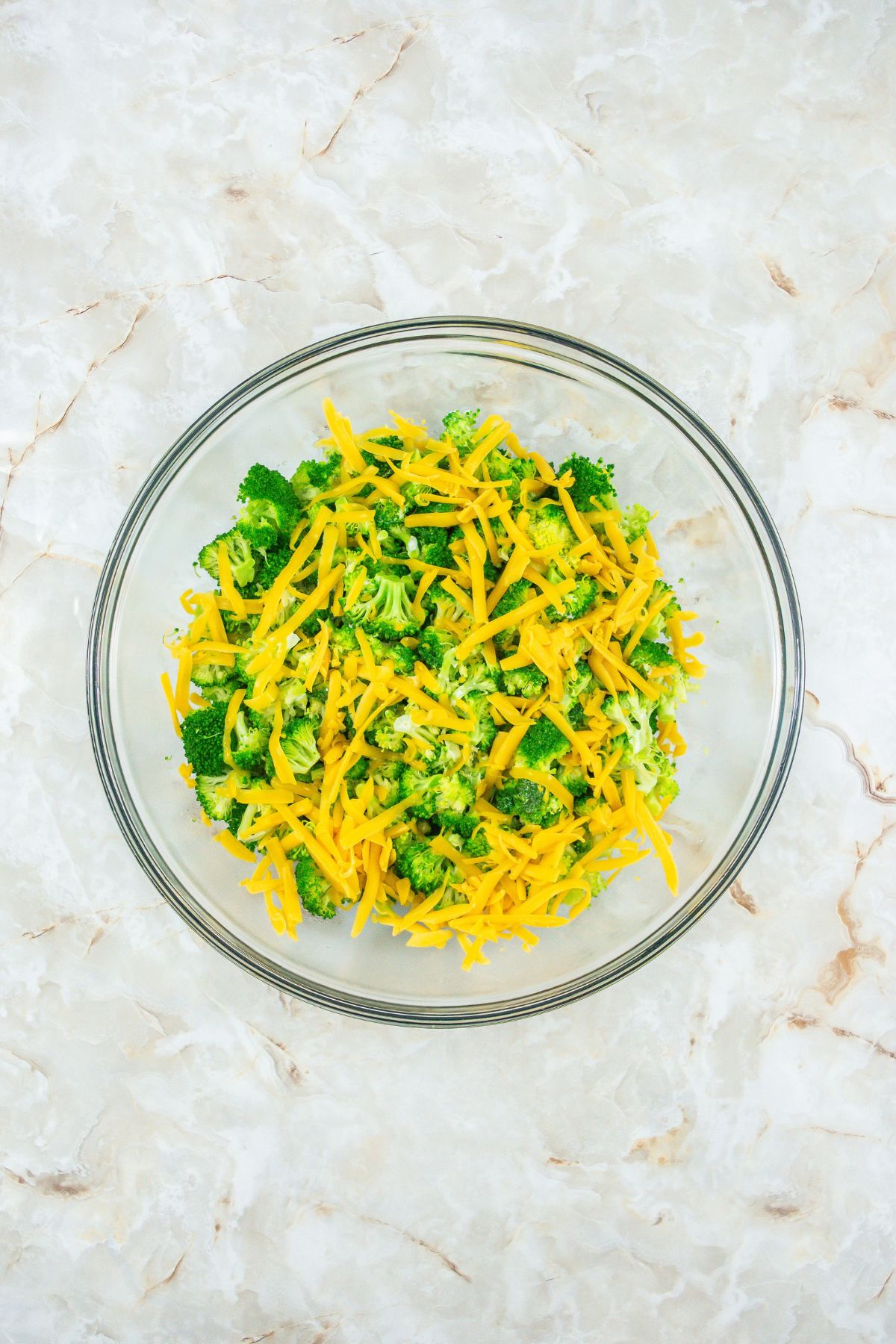Cheese and broccoli mixed in a bowl.