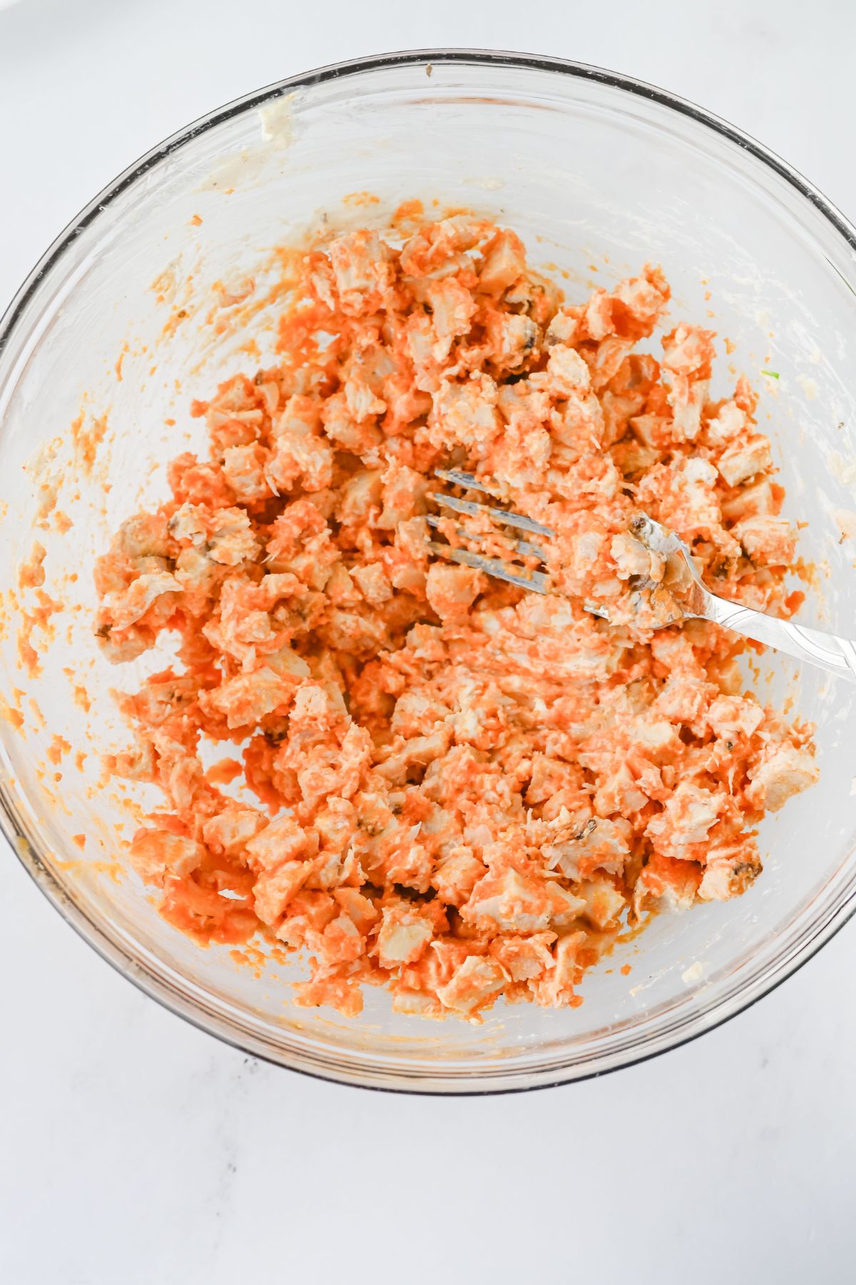 Sauce added to chicken in a bowl.