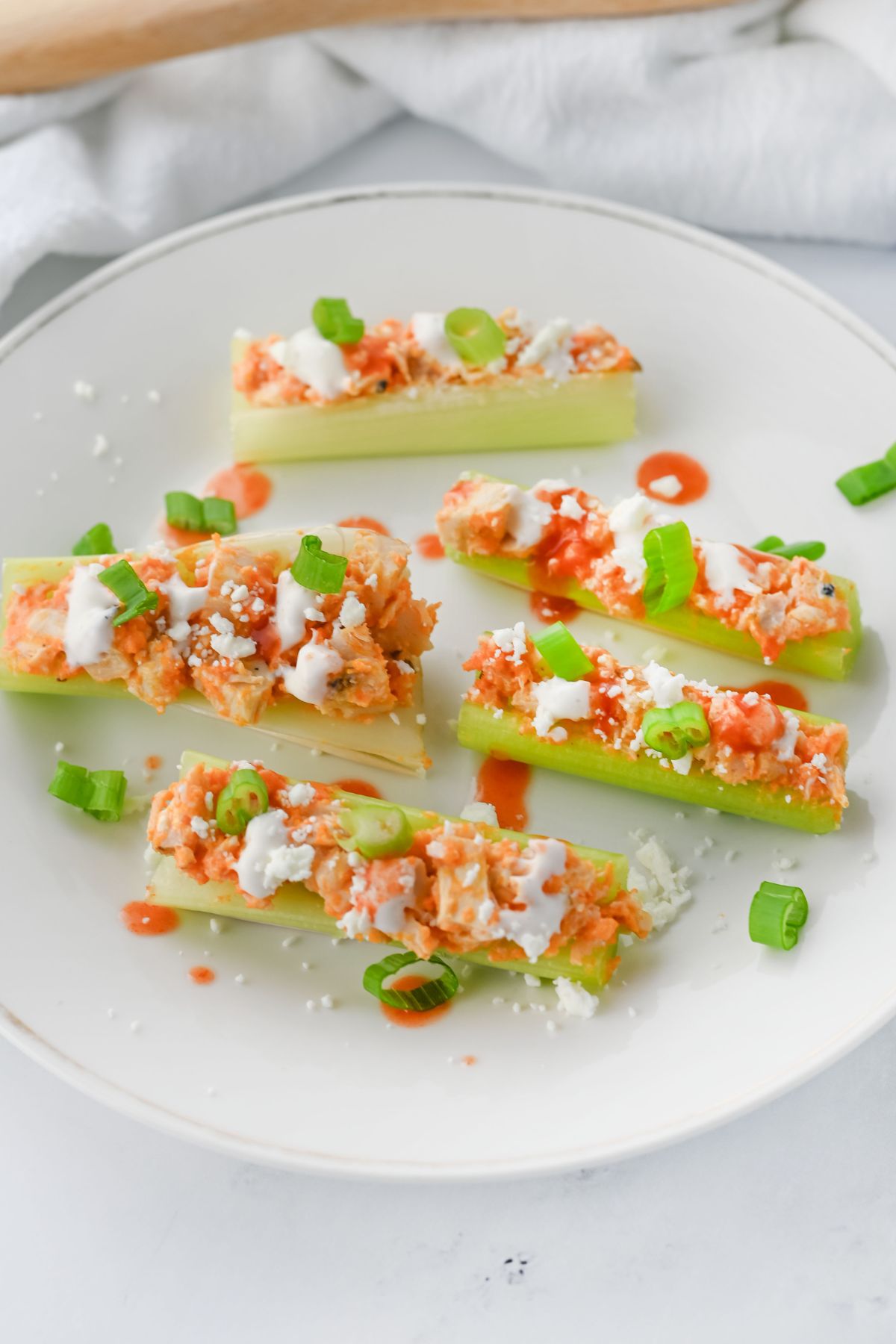 Buffalo chicken celery sticks on a white plate.