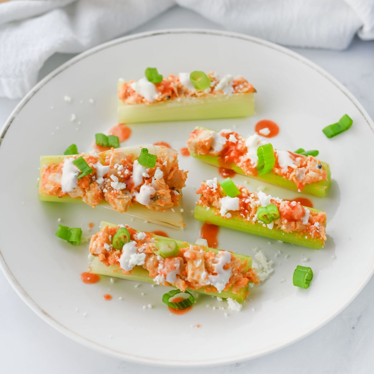 Buffalo chicken celery sticks on a white plate.