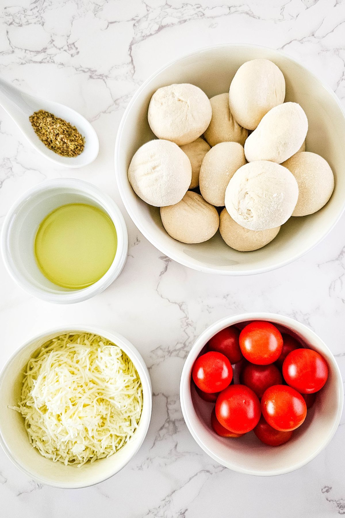 Cheesy tomato focaccia ingredients on a marble counter.