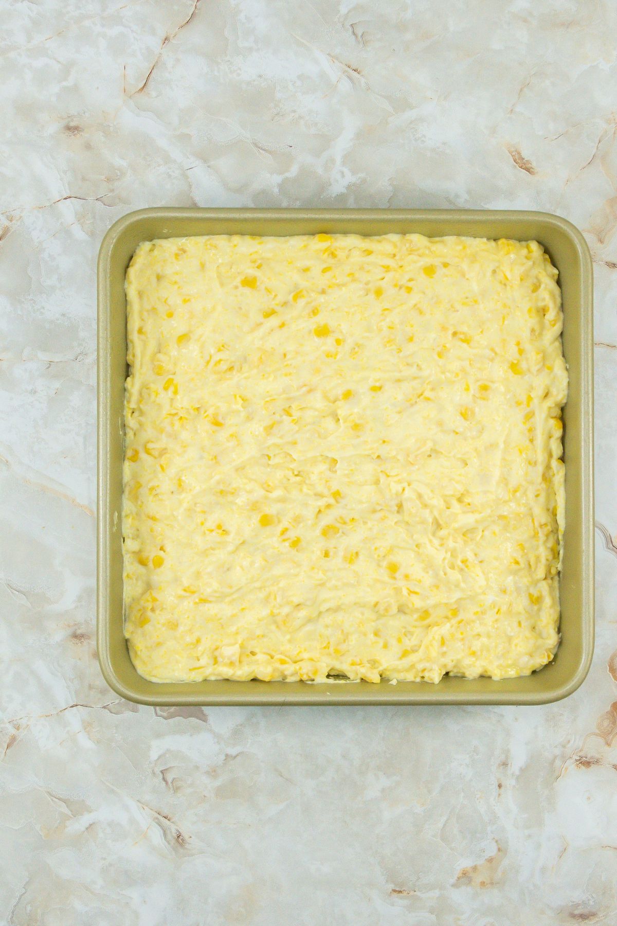 Uncooked corn casserole in a pan.