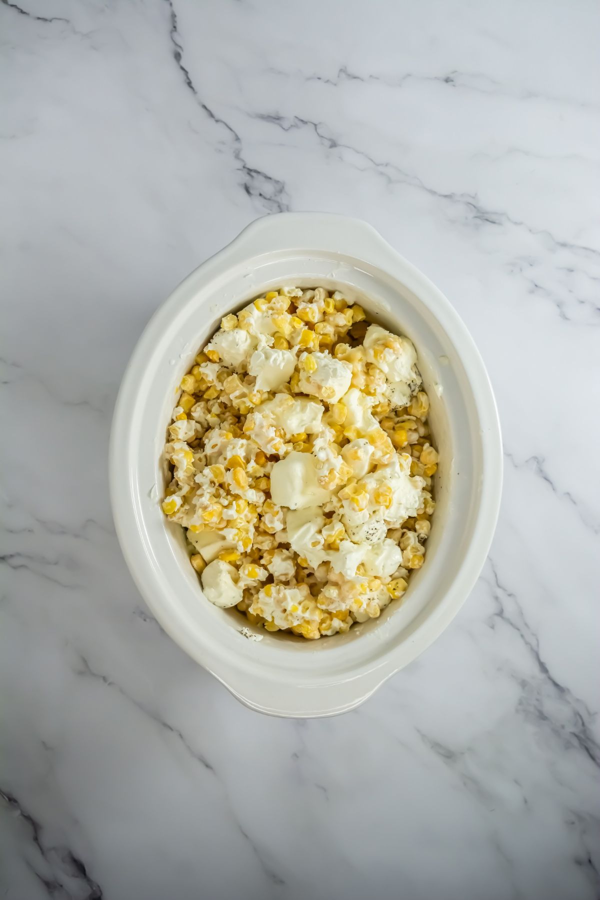 Ingredients on top of corn in slow cooker.