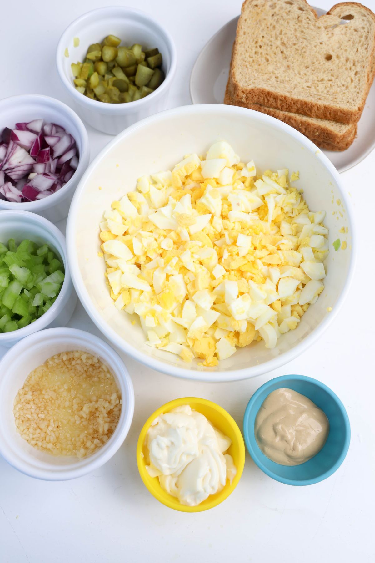 Egg salad tea sandwich ingredients on a white counter.