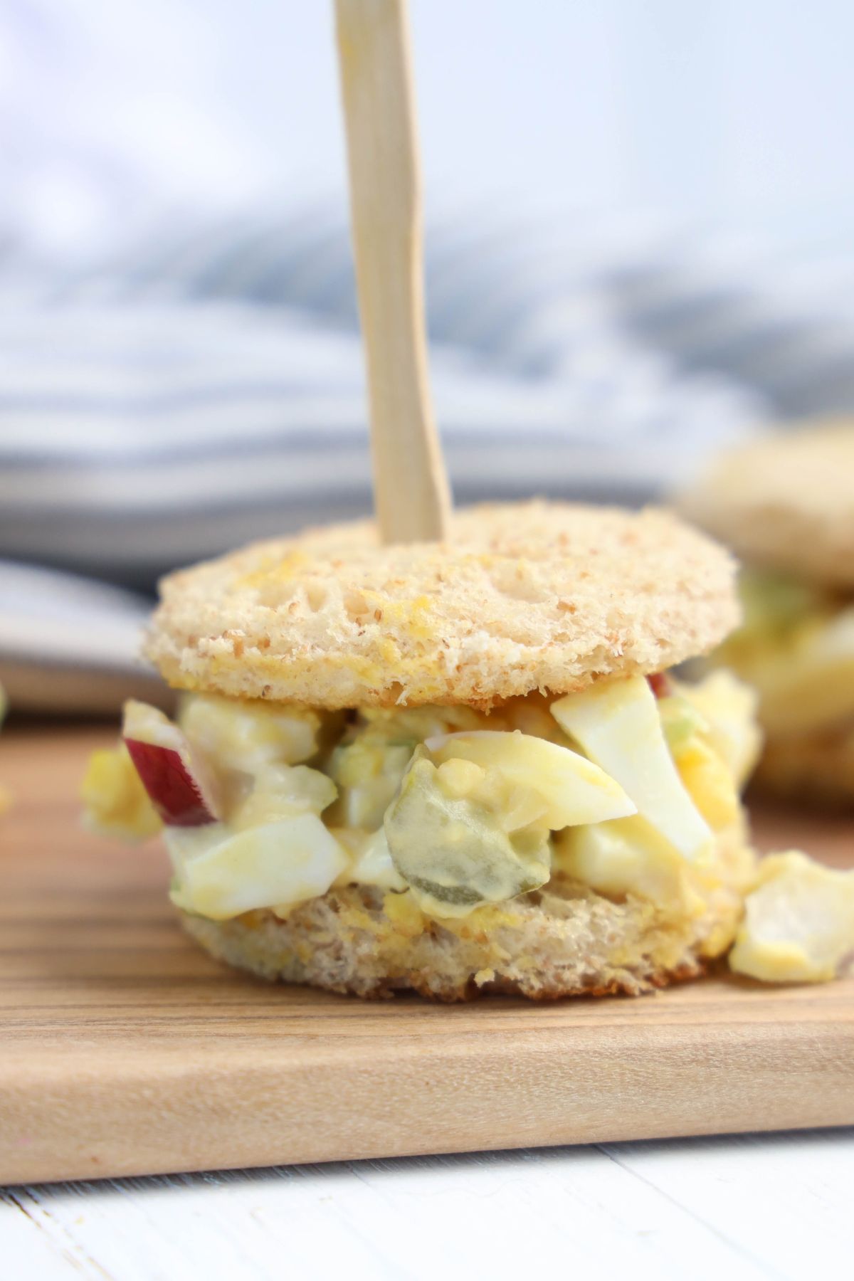 Egg salad tea sandwiches on a wooden board.