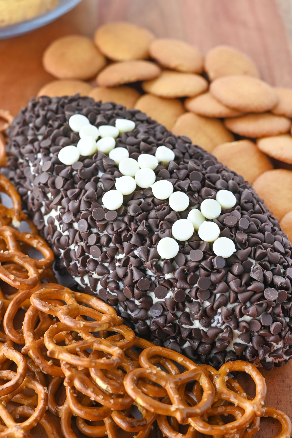 Football cheeseball with pretzels on a wood table.