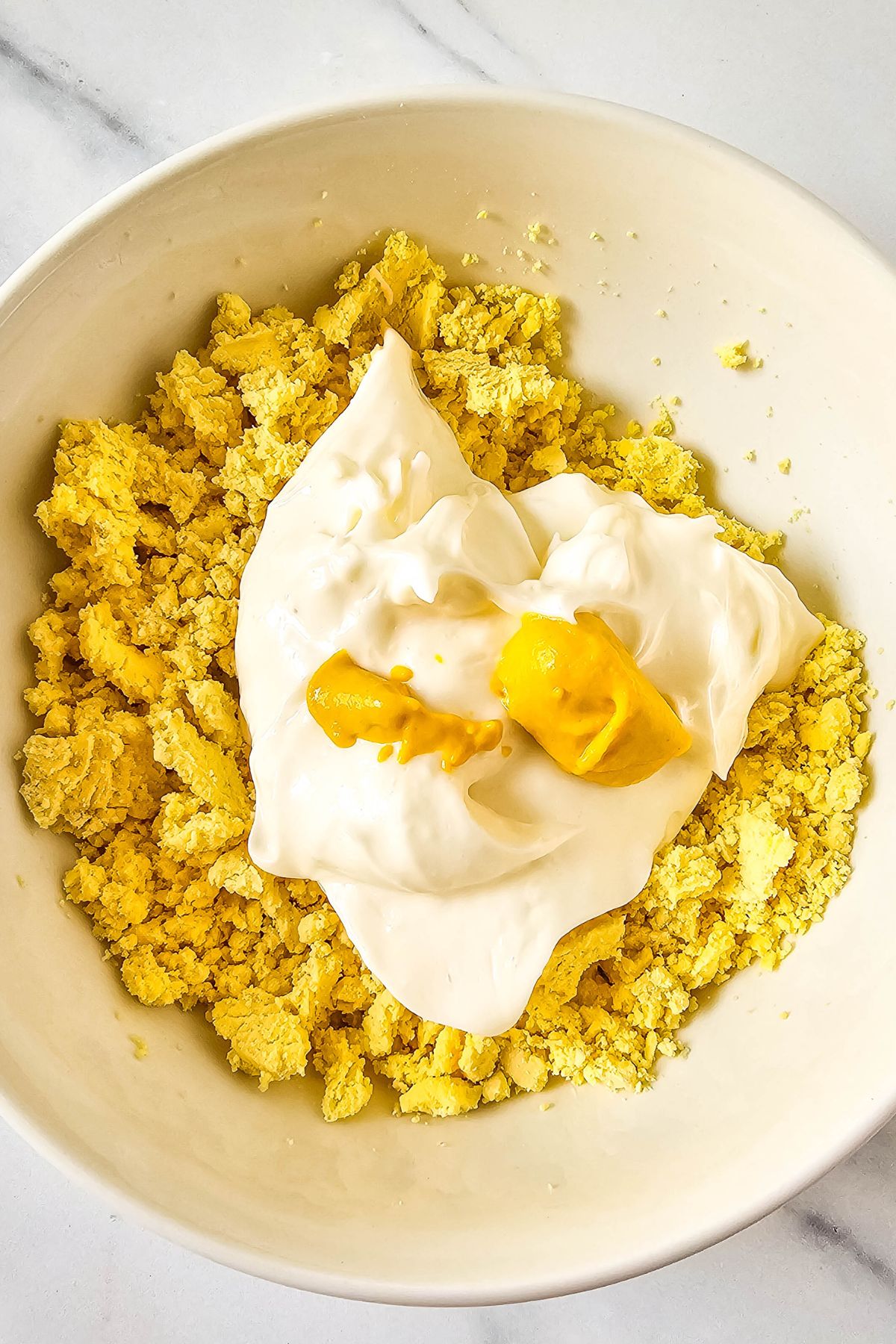 Egg yolks, mayonnaise and mustard in a bowl.