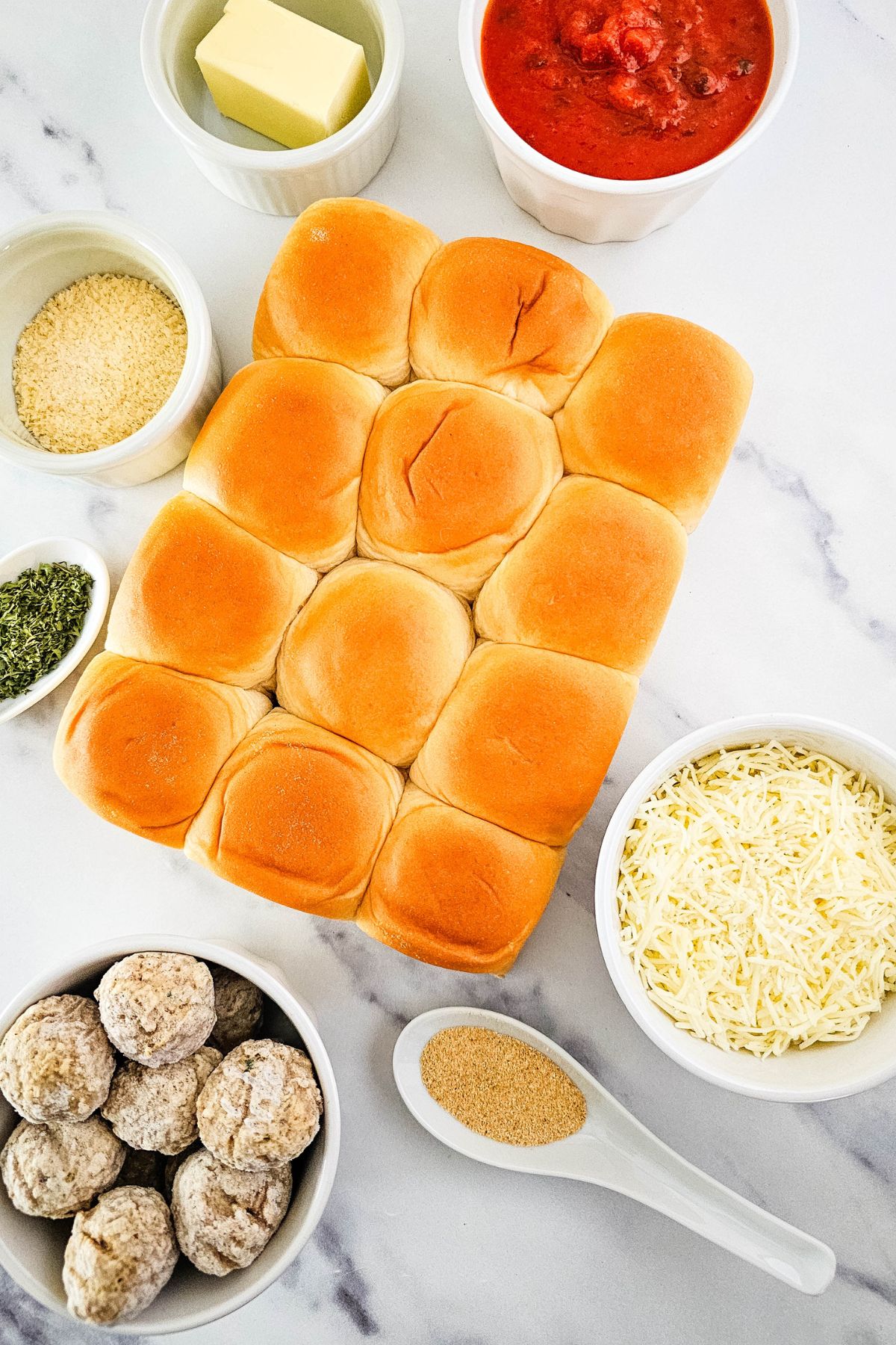 Meatball slider ingredients on a marble table.