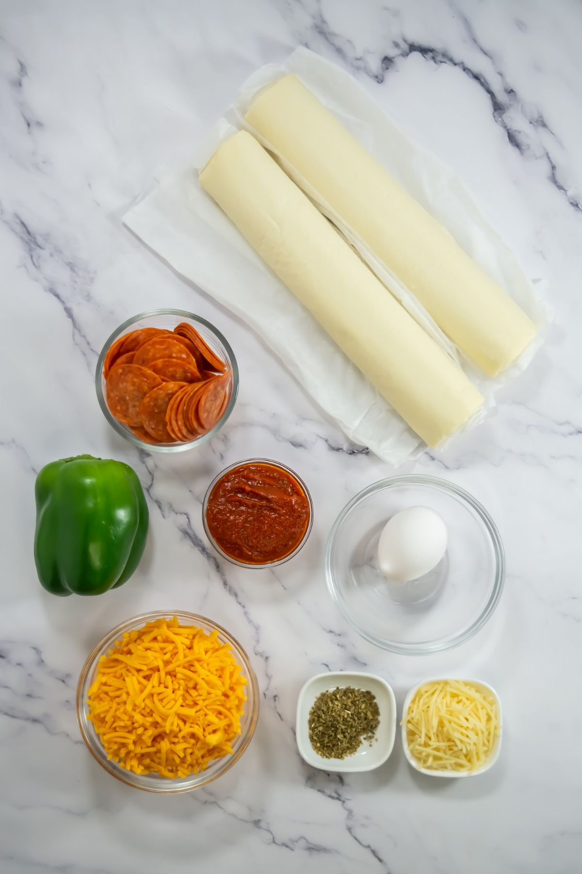 Pizza pinwheel ingredients on a marble counter.
