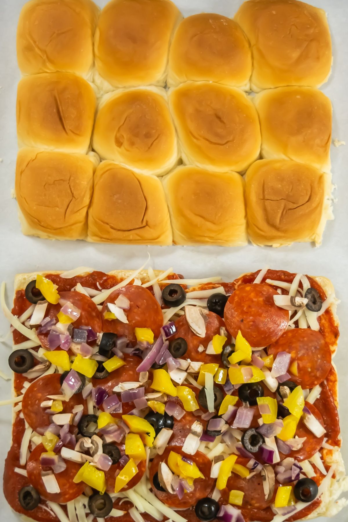 Peppers, onions, olives, pepperoni, cheese and sauce on top of hawaiian rolls.