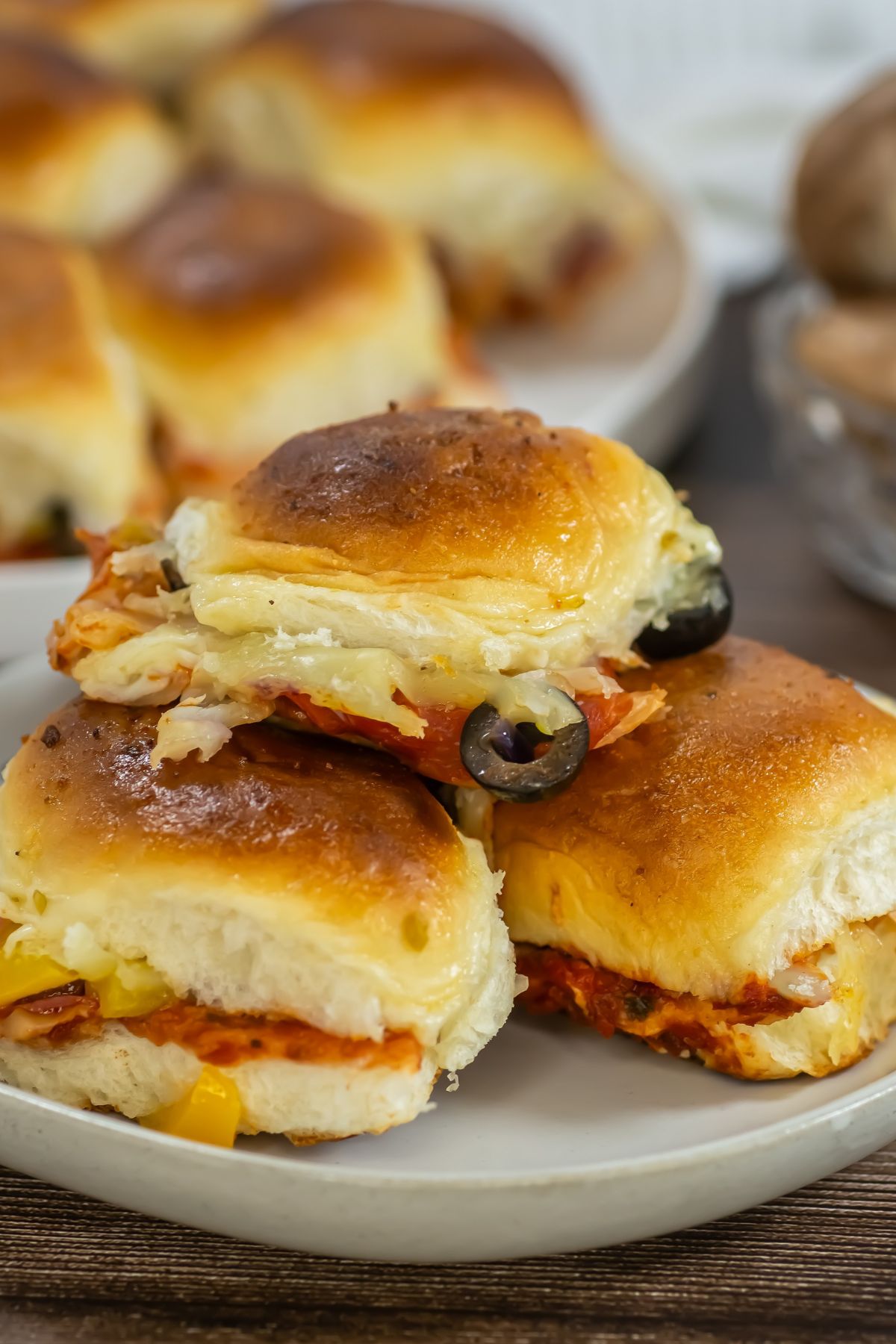 Pizza sliders stacked on a white plate.