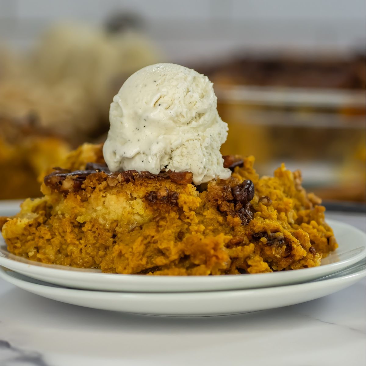 Pumpkin dump cake with ice cream on top on a plate.