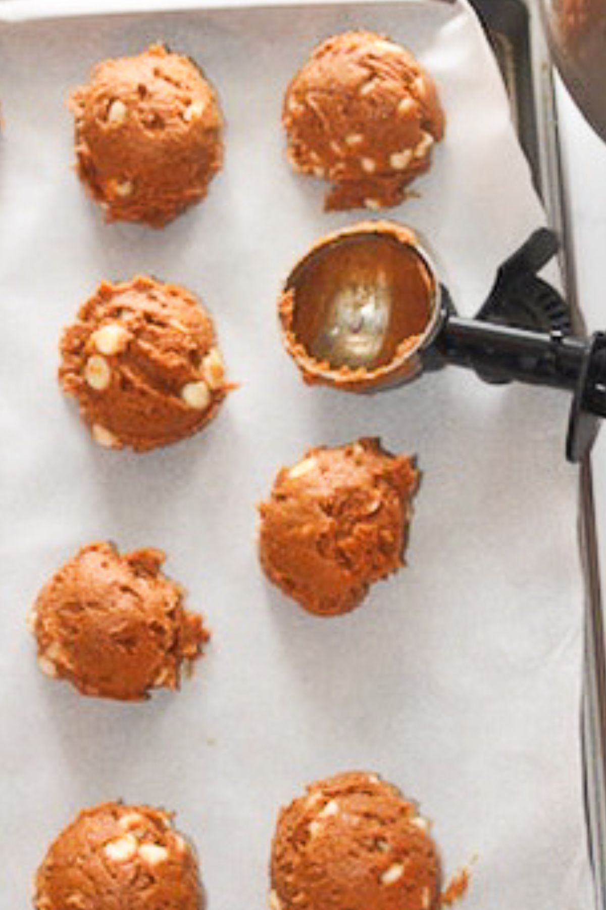 Scooping cookie dough on to parchment paper.