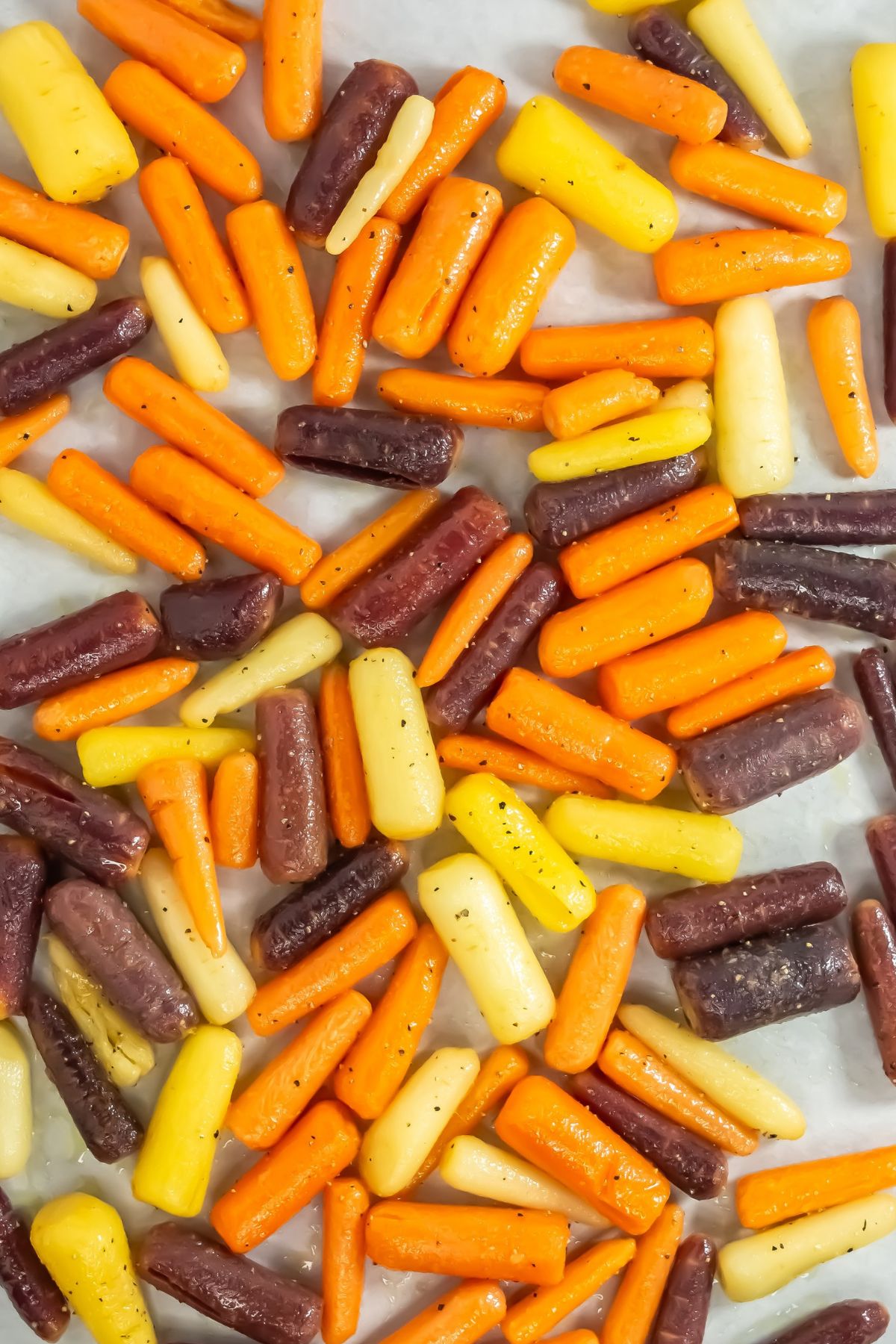 Carrots with spices on a baking sheet.