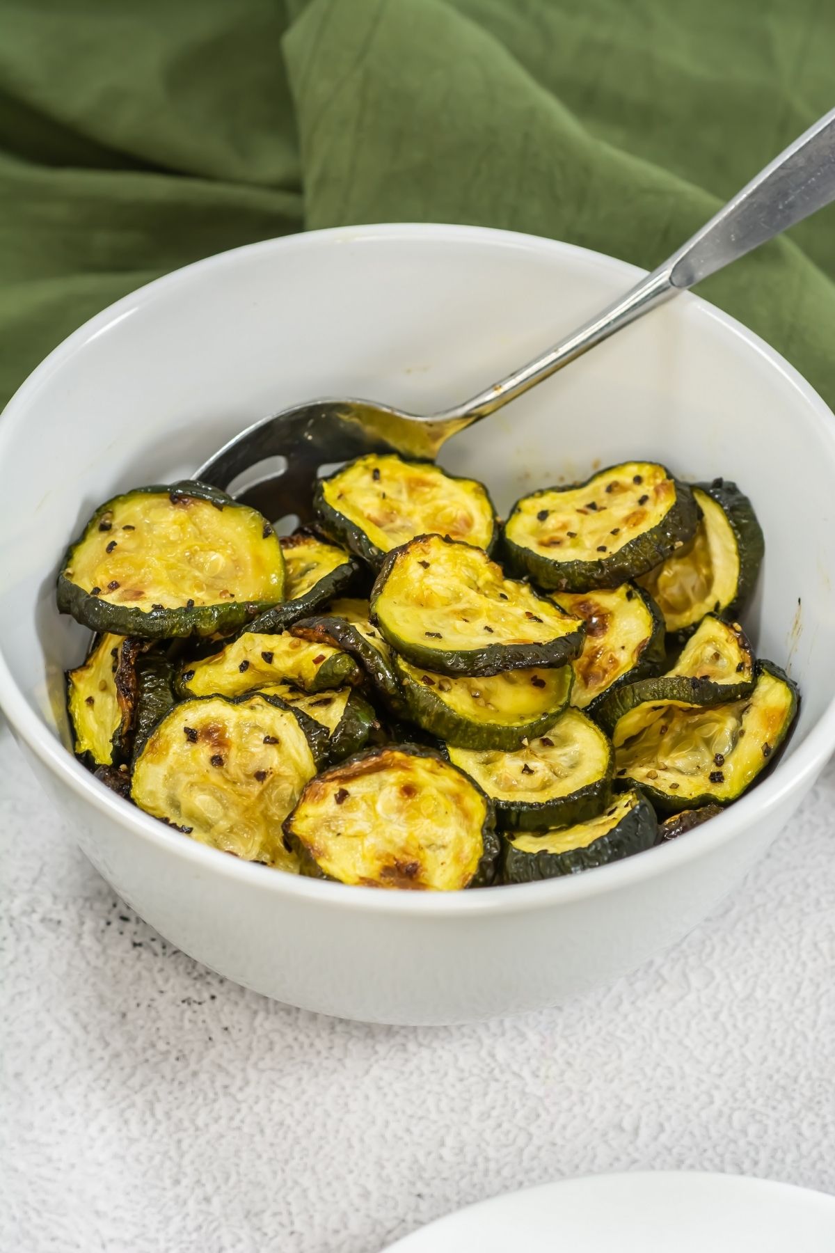 Roasted zucchini in a white bowl.