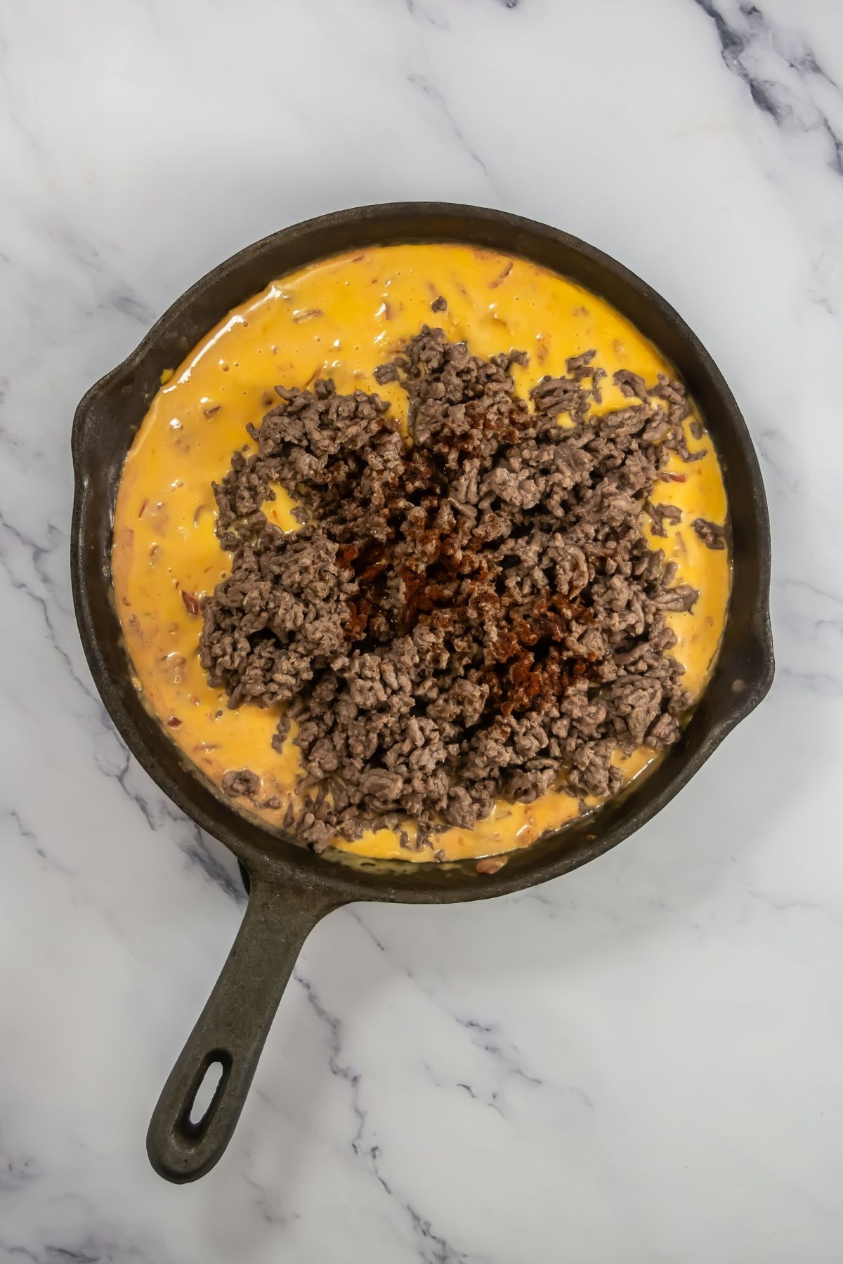 Ground beef and melted cheese in a skillet.