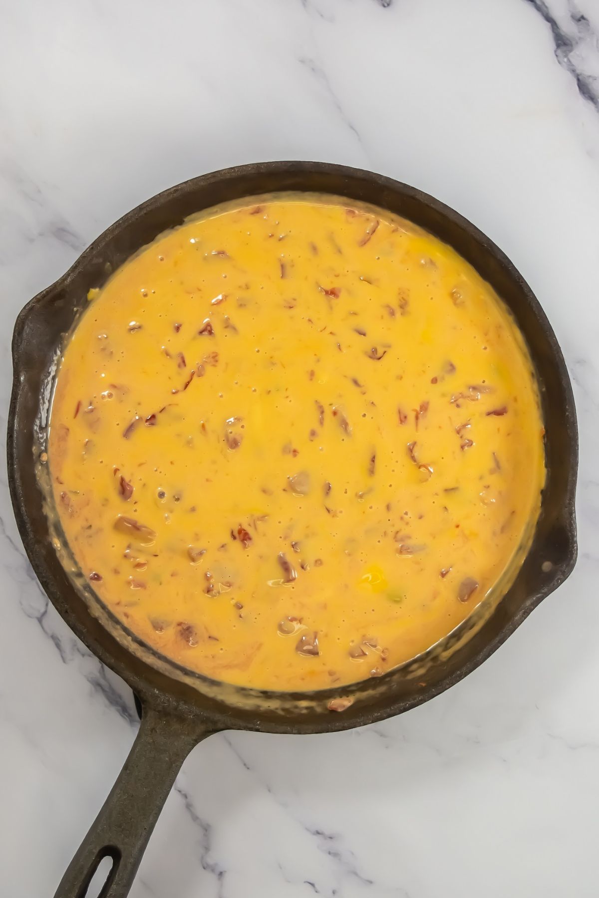 Tomatoes and melted cheese in a skillet.