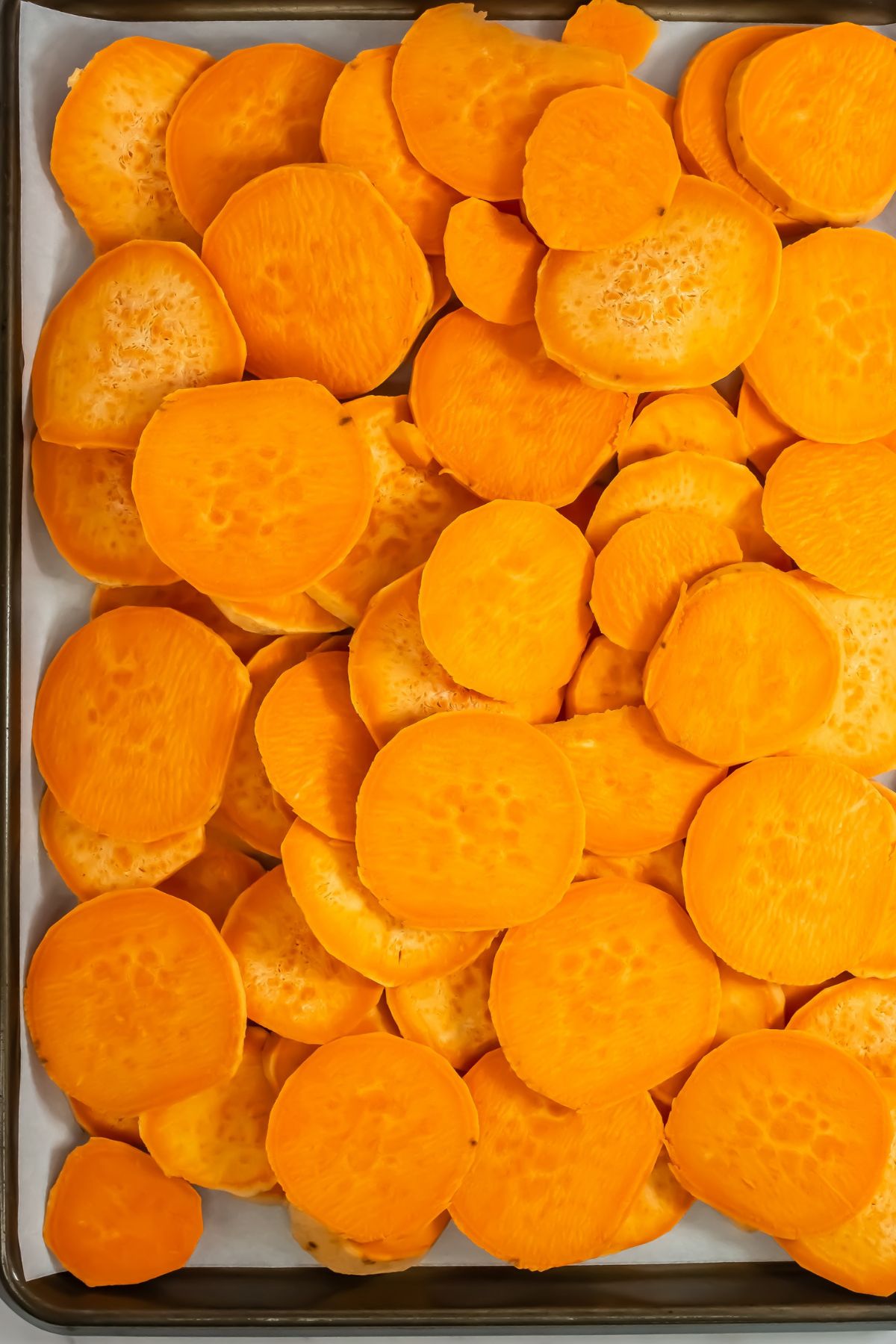 Sliced sweet potatoes on a baking sheet.