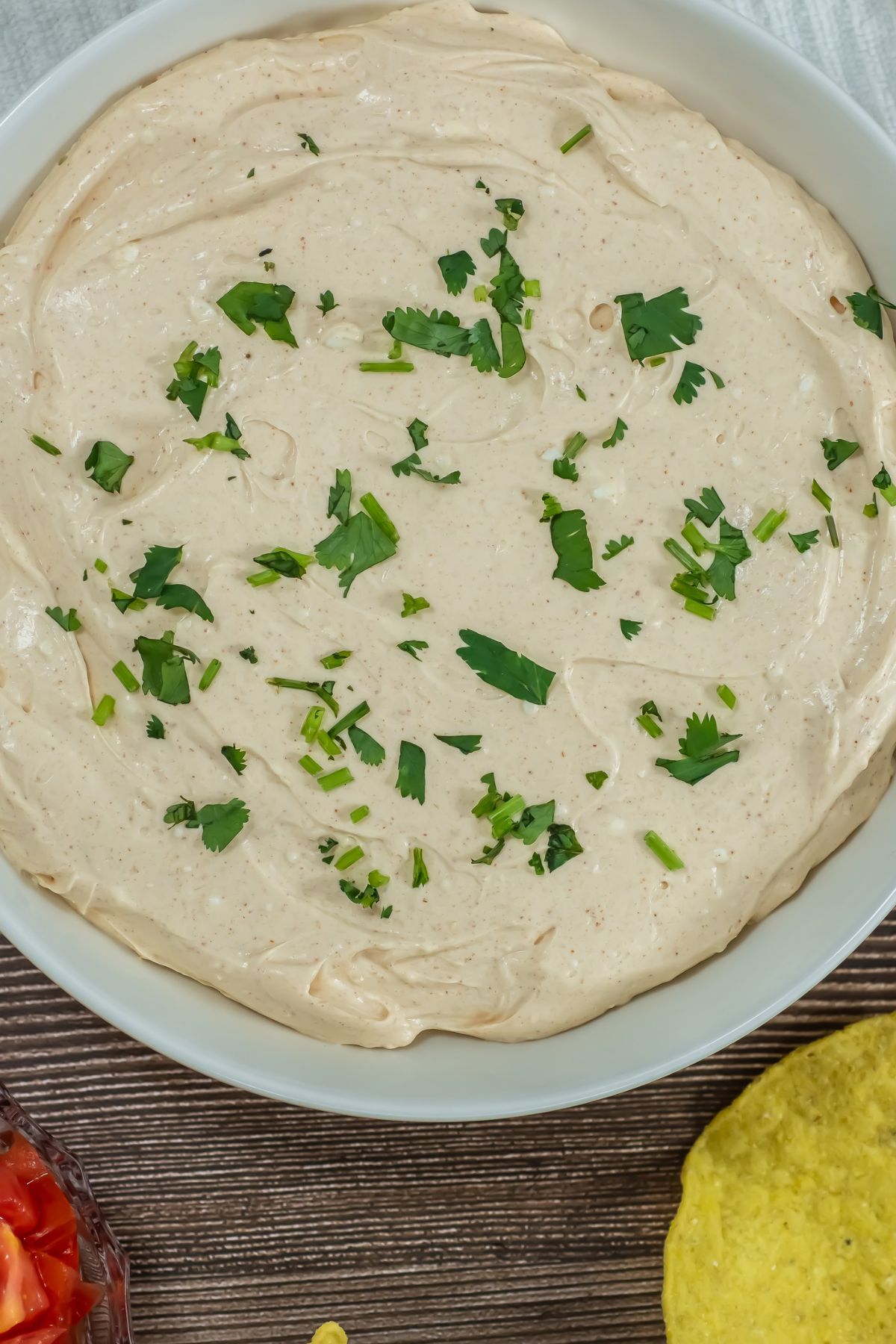 Taco dip in a bowl on a wooden table.