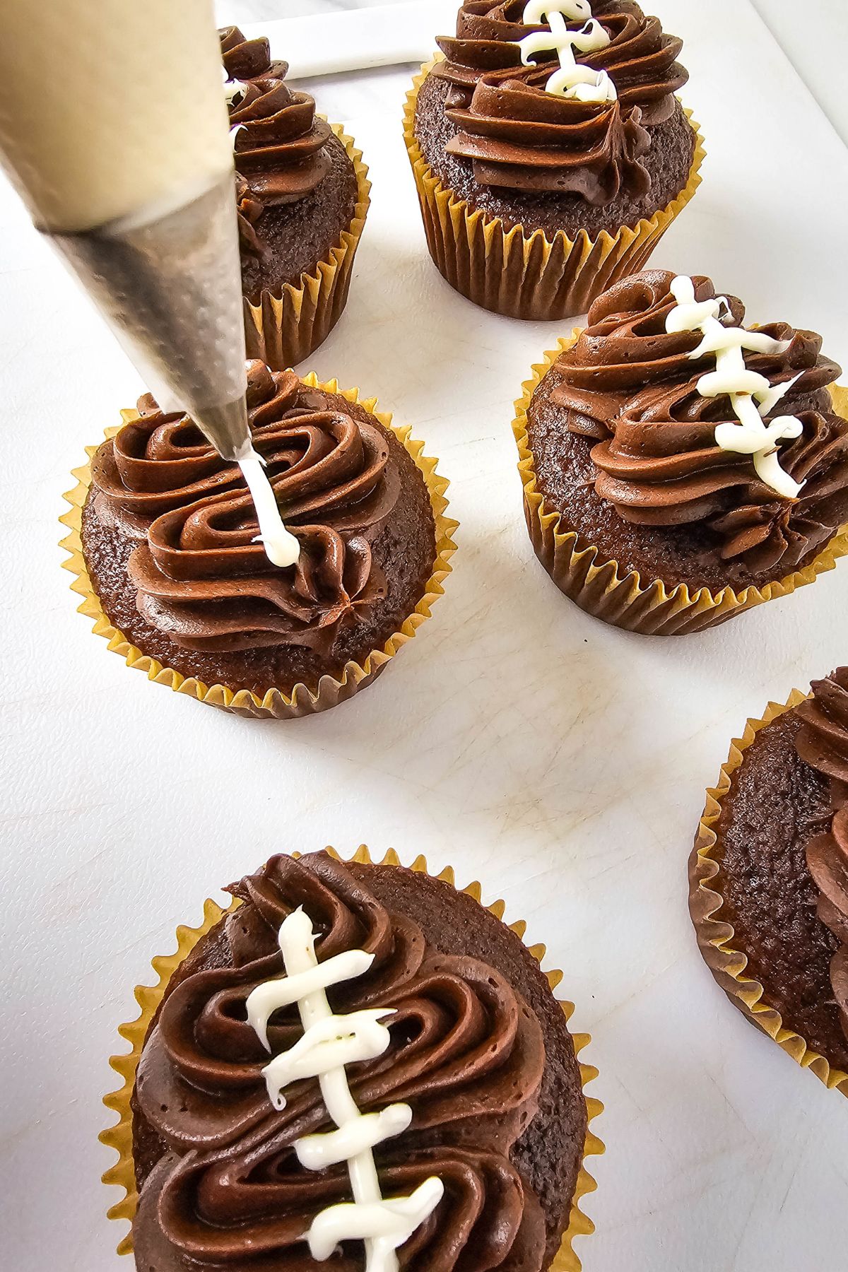 Adding white icing to cupcakes.