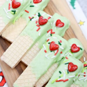Grinch dipped wafers on a wooden board.