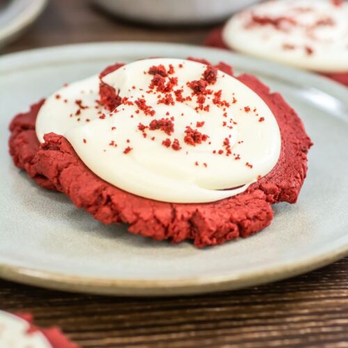 Red velvet cookie with frosting on a plate.