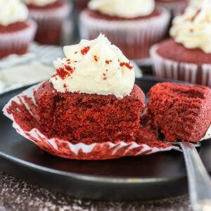 Red velvet cupcake with frosting on a plate.