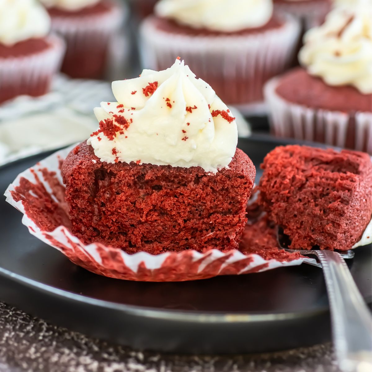 Red velvet cupcake with frosting on a plate.