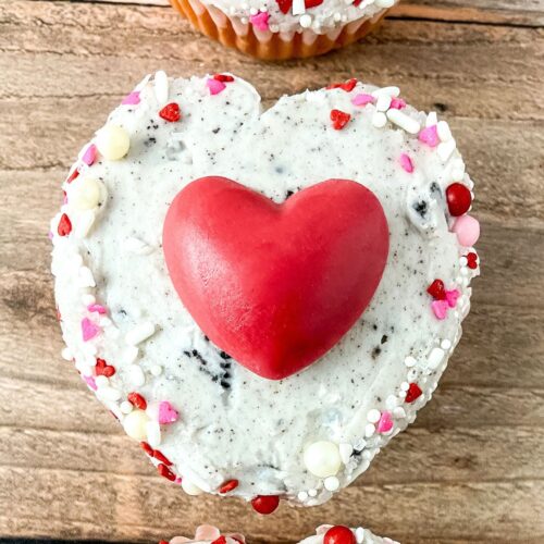 Strawberry and cream cupcakes on a wood surface.