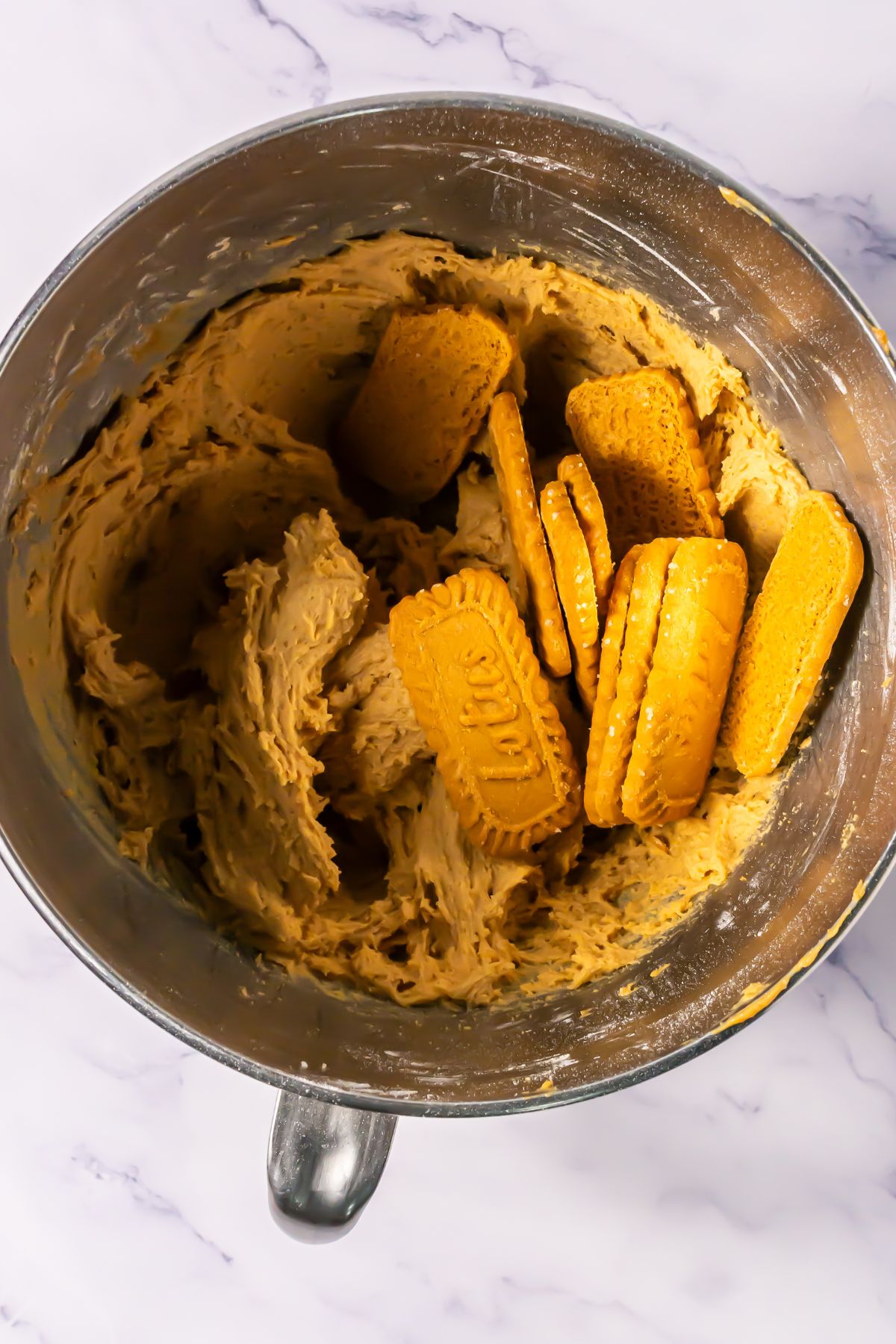 Adding biscoff cookies to cookie dough.