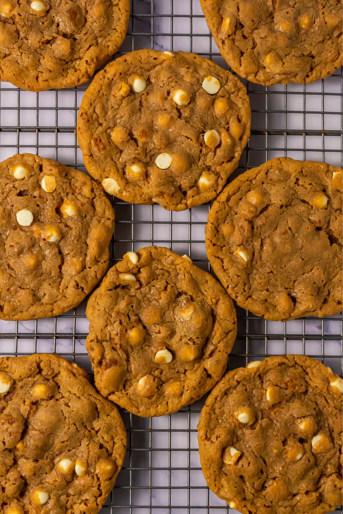 Crumbl biscoff white chocolate chip cookies on a cooling rack.