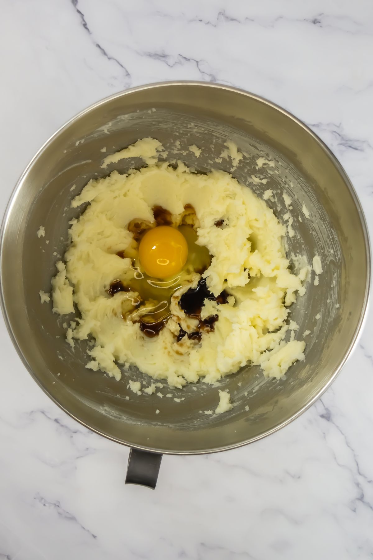 Adding eggs and vanilla into cookie dough.