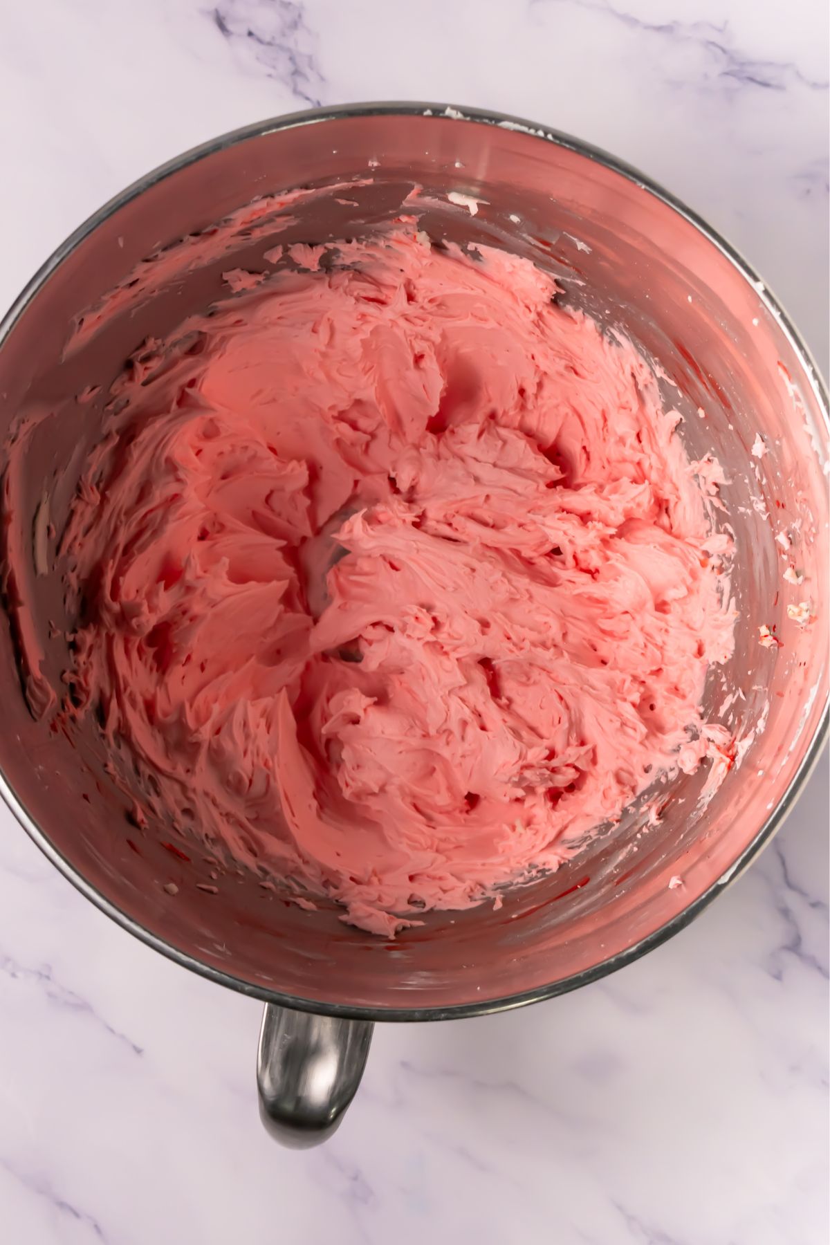 Pink frosting in a mixing bowl.