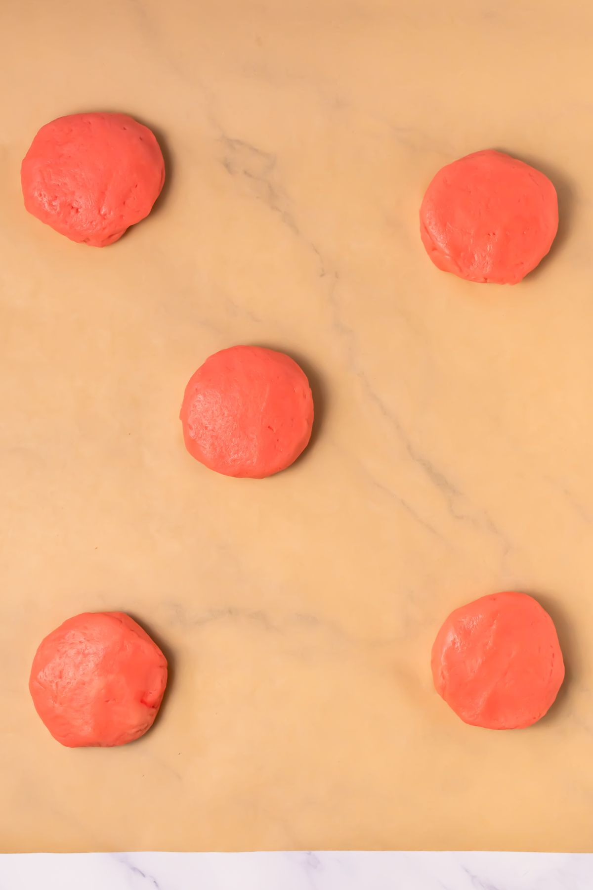 Pink velvet cookie dough on parchment paper.