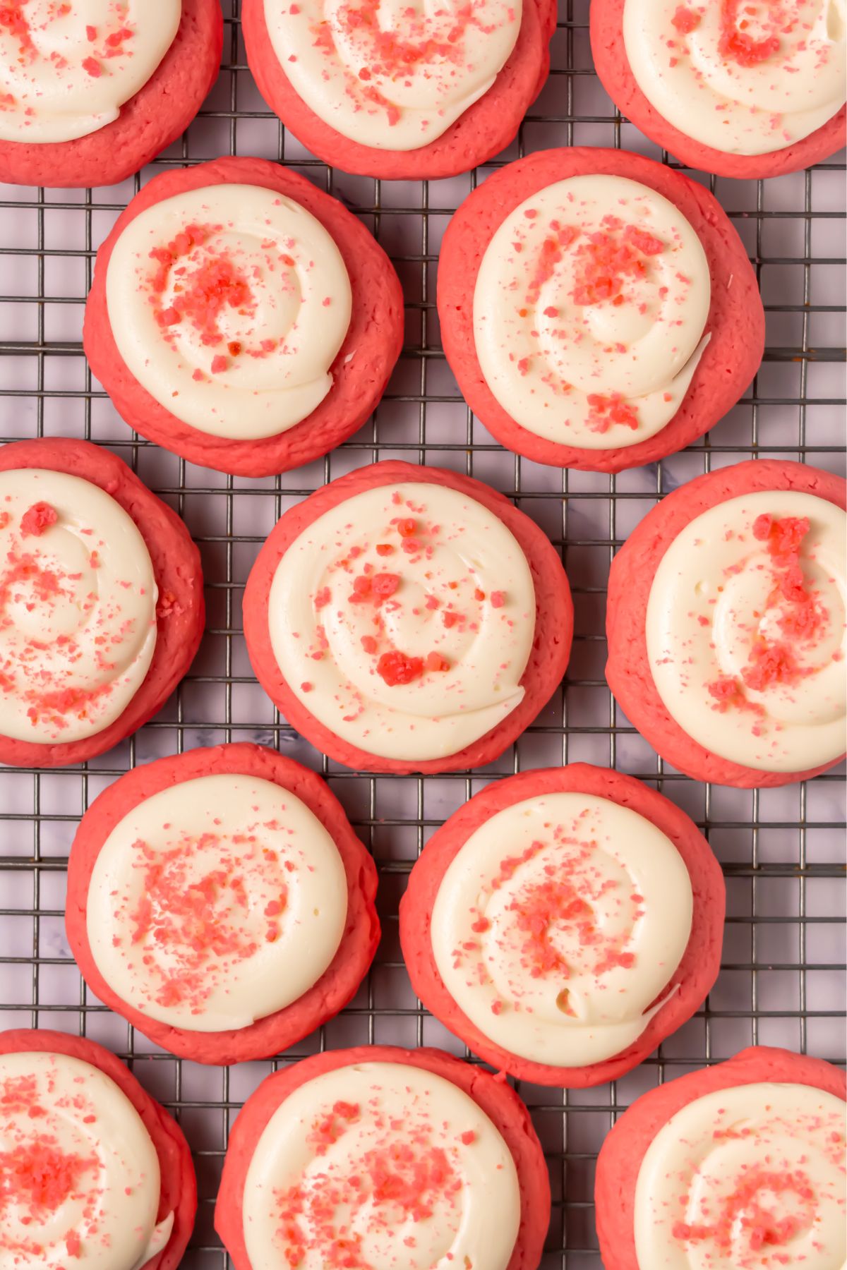 Crumbl pink velvet cookies on a cooling rack.
