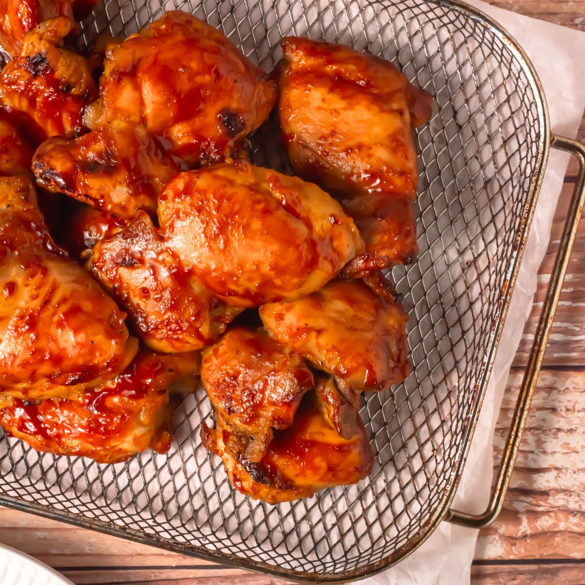 Air fryer BBQ chicken thighs in a basket.