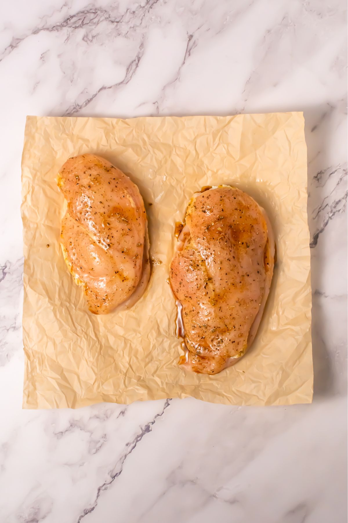 Seasoned chicken breast on parchment paper.