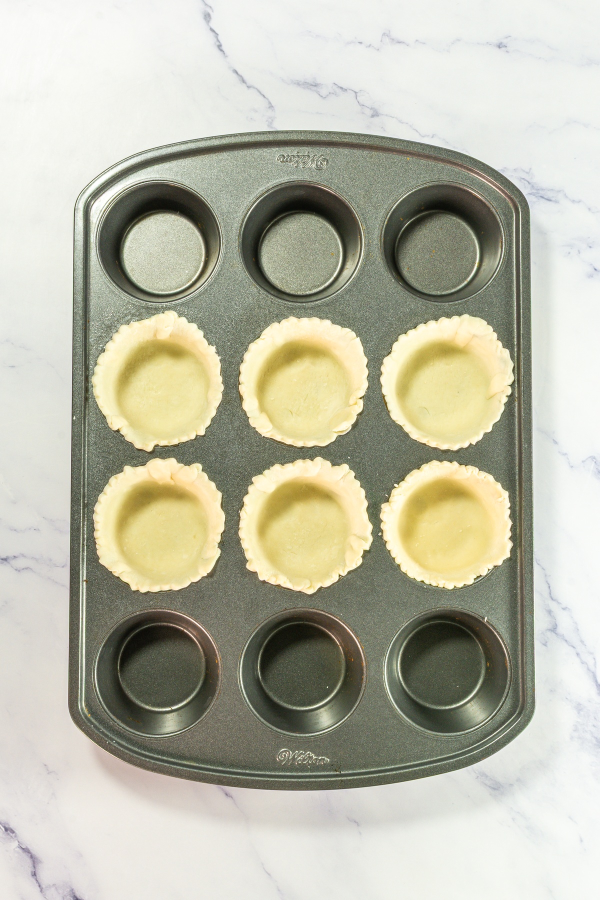 Pie crusts added into cupcake tin.