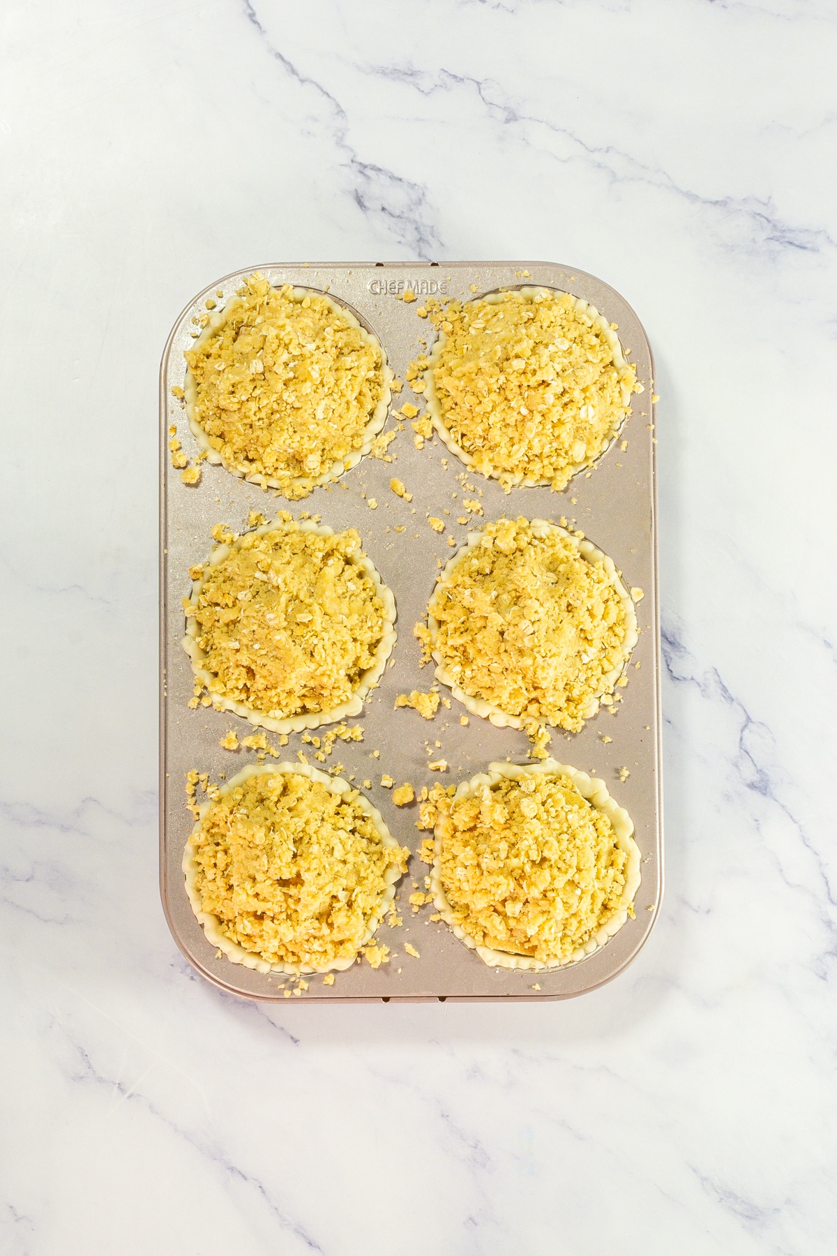 Apple pie crumble sprinkled on top of pies.