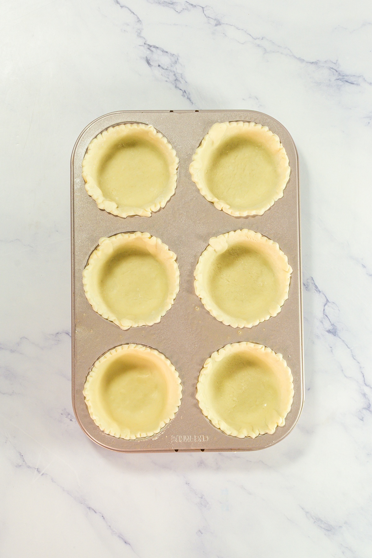 Pie crusts added into cupcake tin.