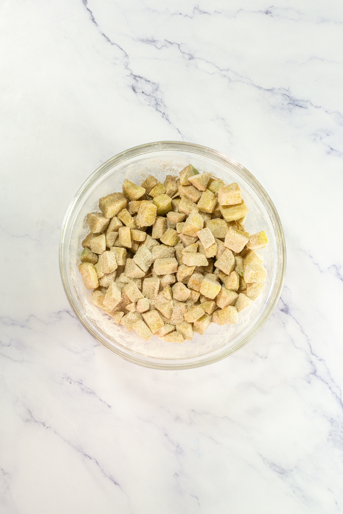 Apple slices tossed in spices in a bowl.