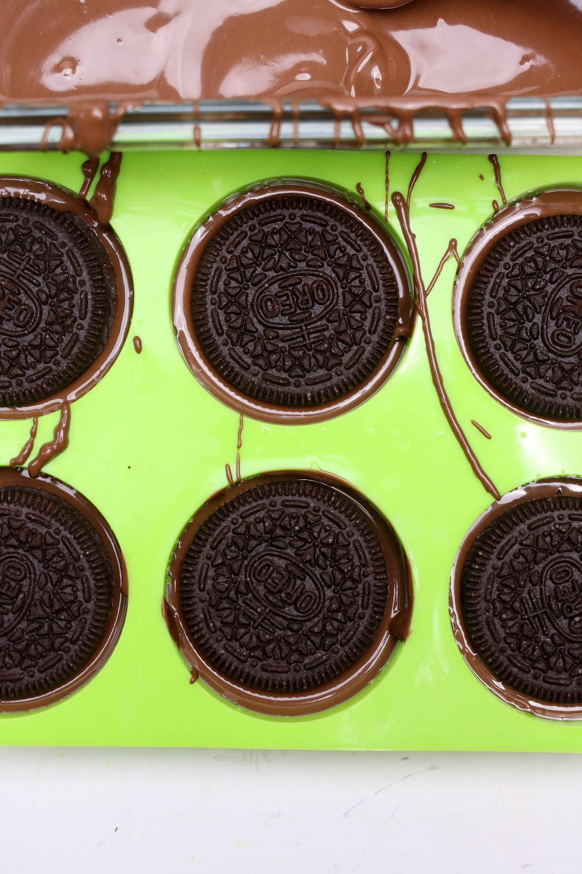 Oreos on top of melted chocolate in a mold.