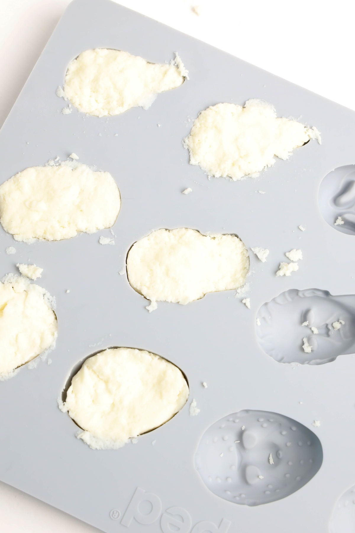 A gray silicone mold with Halloween horror face shapes filled with cheese.