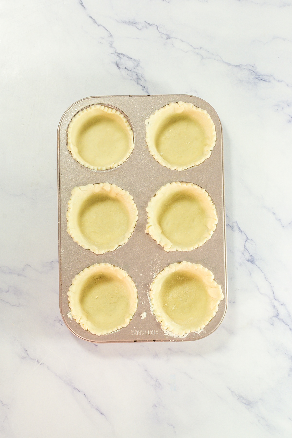 Pie crusts added into cupcake tin.