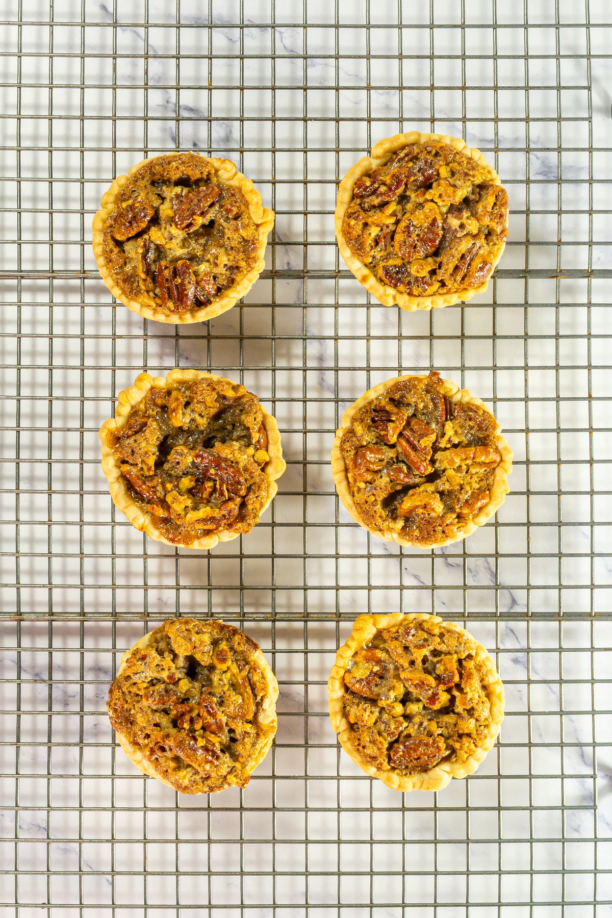 Mini pecan pies on a cooling rack.