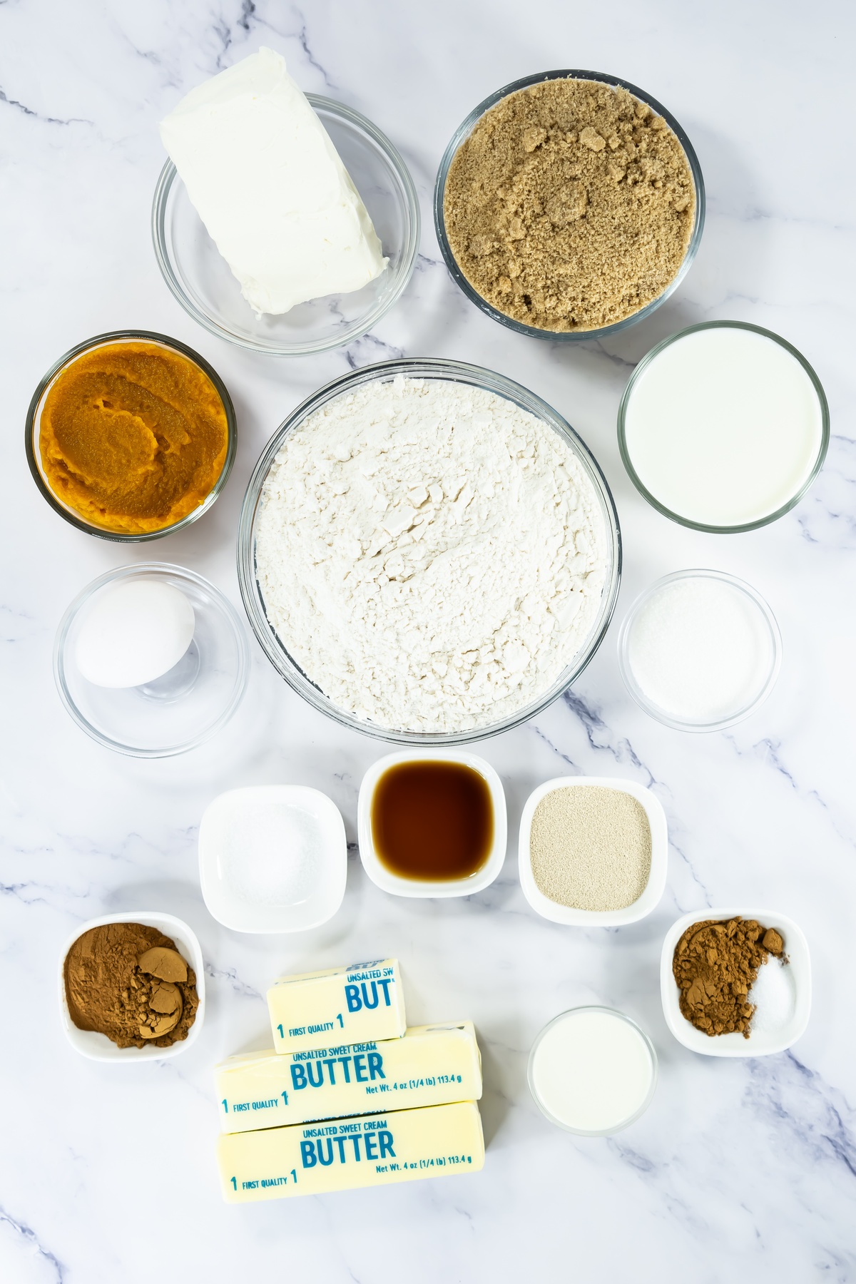 Ingredients for pumpkin cinnamon rolls: flour, brown sugar, cream cheese, pumpkin puree, milk, sugar, butter, vanilla.