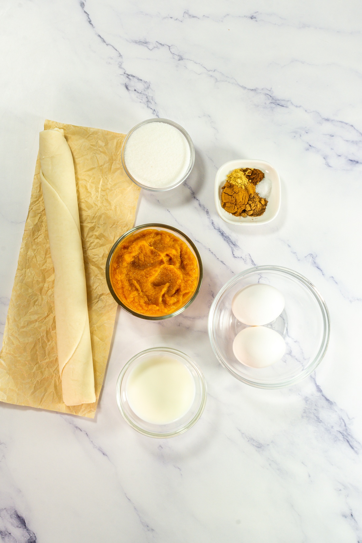 Mini pumpkin pie ingredients on a marble counter.