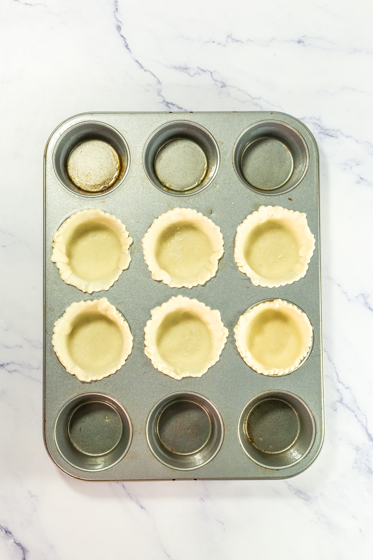 Pie crusts added into cupcake tin.