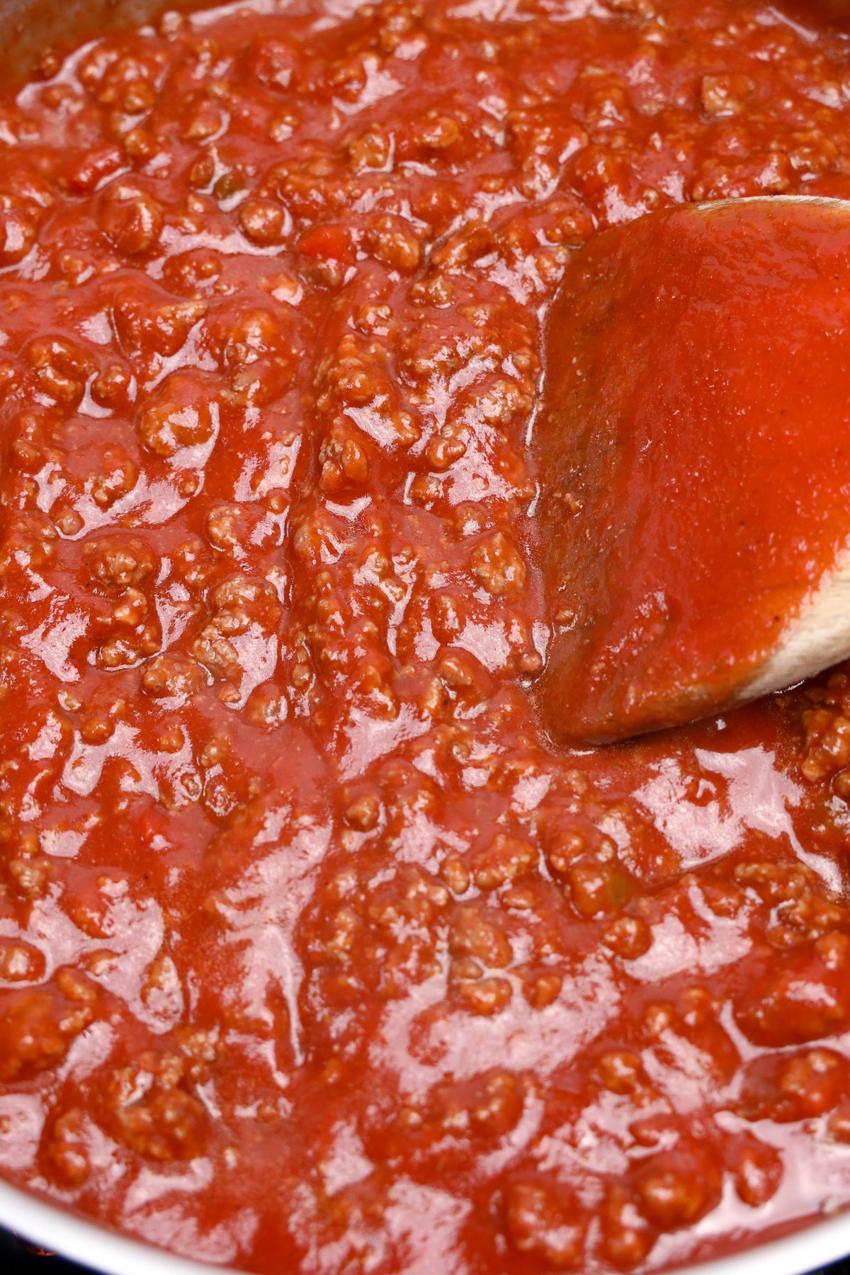 Marinara sauce added to ground beef in a pan.